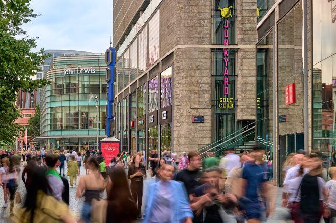 "Busy Liverpool ONE street with shoppers walking past stores including Junkyard Golf Club and John Lewis."