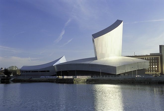External view of IWM North. The building has a curved roof and the image is from across the water.