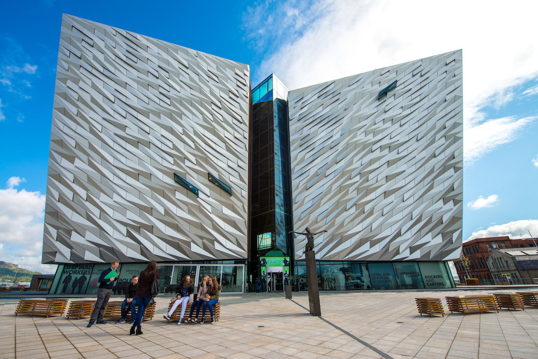 "Queen's University Belfast building, large silver outer surface of building with outdoor student seating"