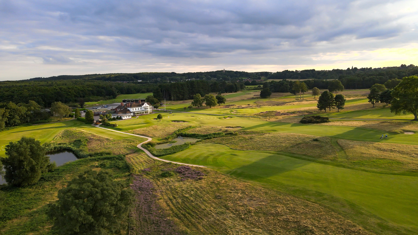 Aerial view of the golf course with the building and car park behind.