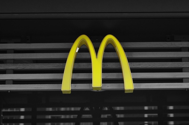 "Photo showing the McDonald's large 'M' symbol in yellow above an entrance. There are grey panels behind it."