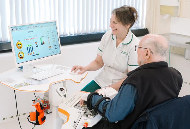 "A patient receiving therapy with a nurse on a computer"