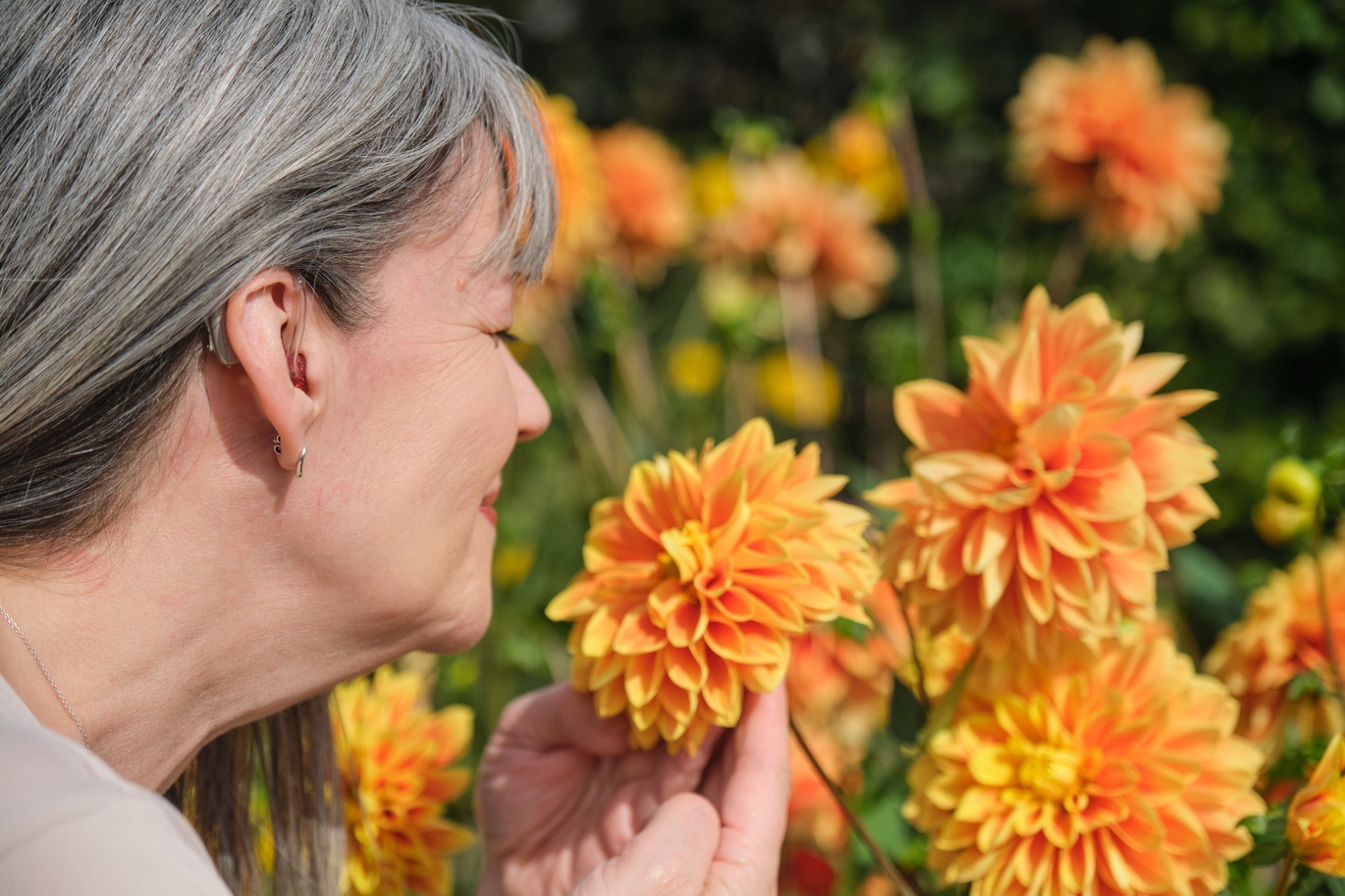 "Femme person smelling beautiful orange flowers"