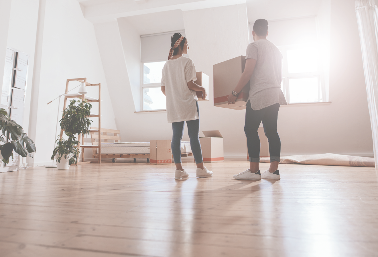 A couple moving empty boxes into a new house