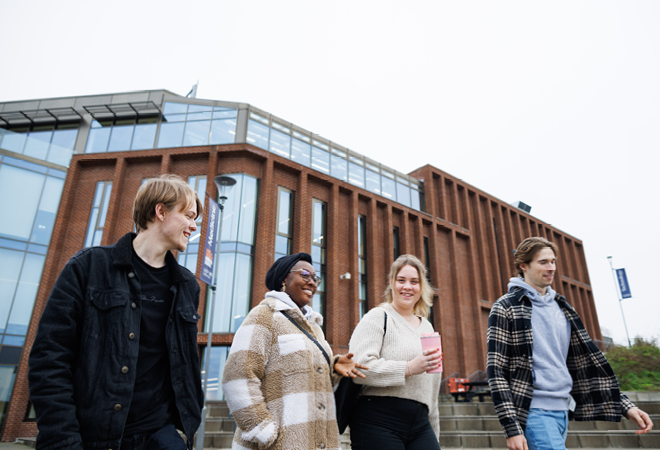 "Image of four students walking in front of an iconic CCCU Building"