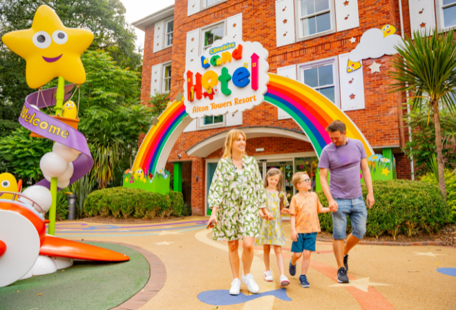 "Family walking under rainbow entrance to CBeebies Land Hotel at Alton Towers Resort."