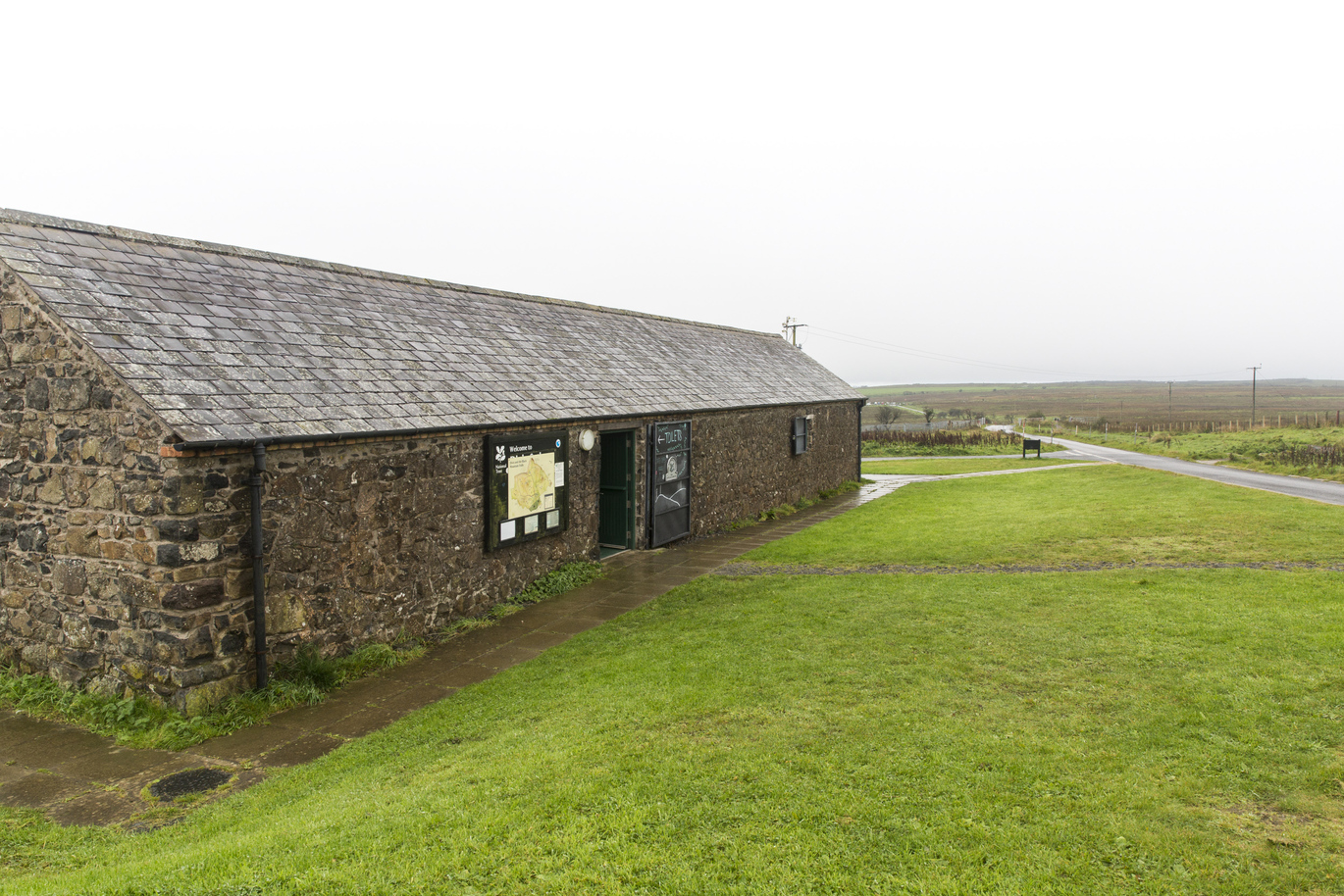Exterior of the stone built café at Divis and the Black Mountain with lawns around it on a misty day.