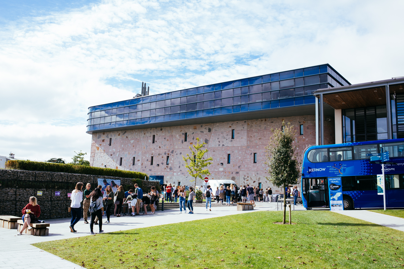 "Exterior image of Penryn campus with lots of students sitting on grass in the foreground"