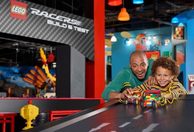 "kid playing with cars along with a man"