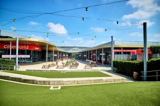 "Outdoor plaza at White Rose with seating, string lights and Cineworld and restaurants on either side."