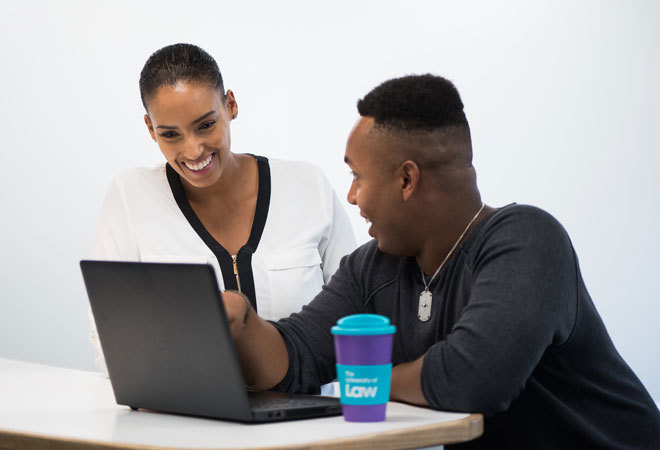 two people working on a laptop, with a university of law branded thermos in view.