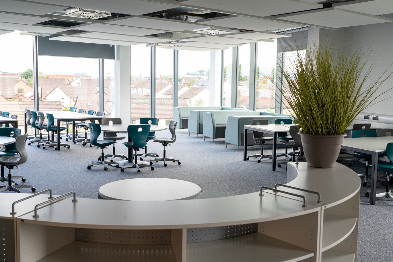A bright study room with a variety of tables and seating options such as sofa boothes and traditional meeting desks