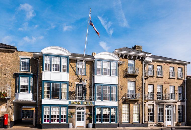 "External view of Swan Hotel - a yellow brick building with a large flagpole and blue framed windows"