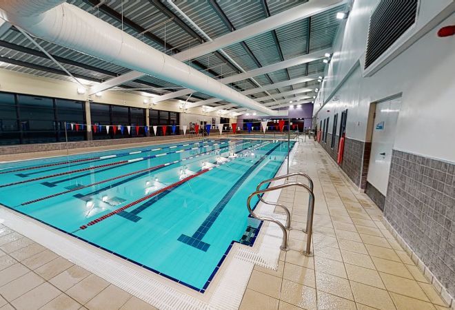 ''swimming pool with red, white and blue flags going across. pool has steps at the end''