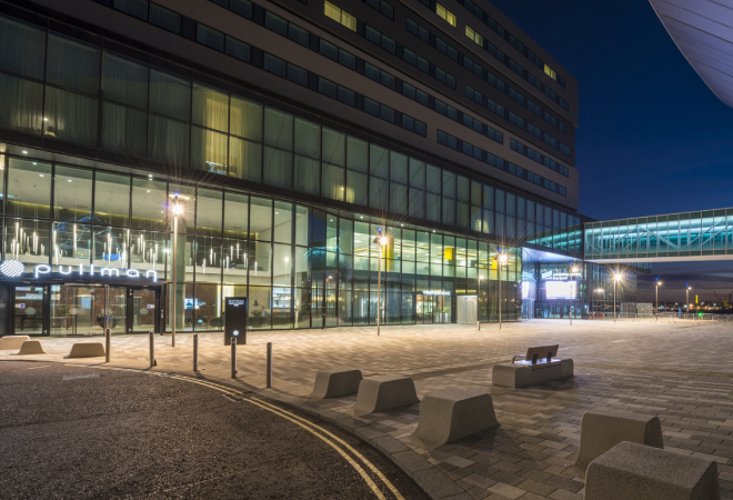 "Building with multiple glass windows. To the left of the building is an entrance with the name Pullman above"