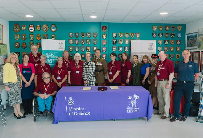 "Veterans and staff standing behind a table display"