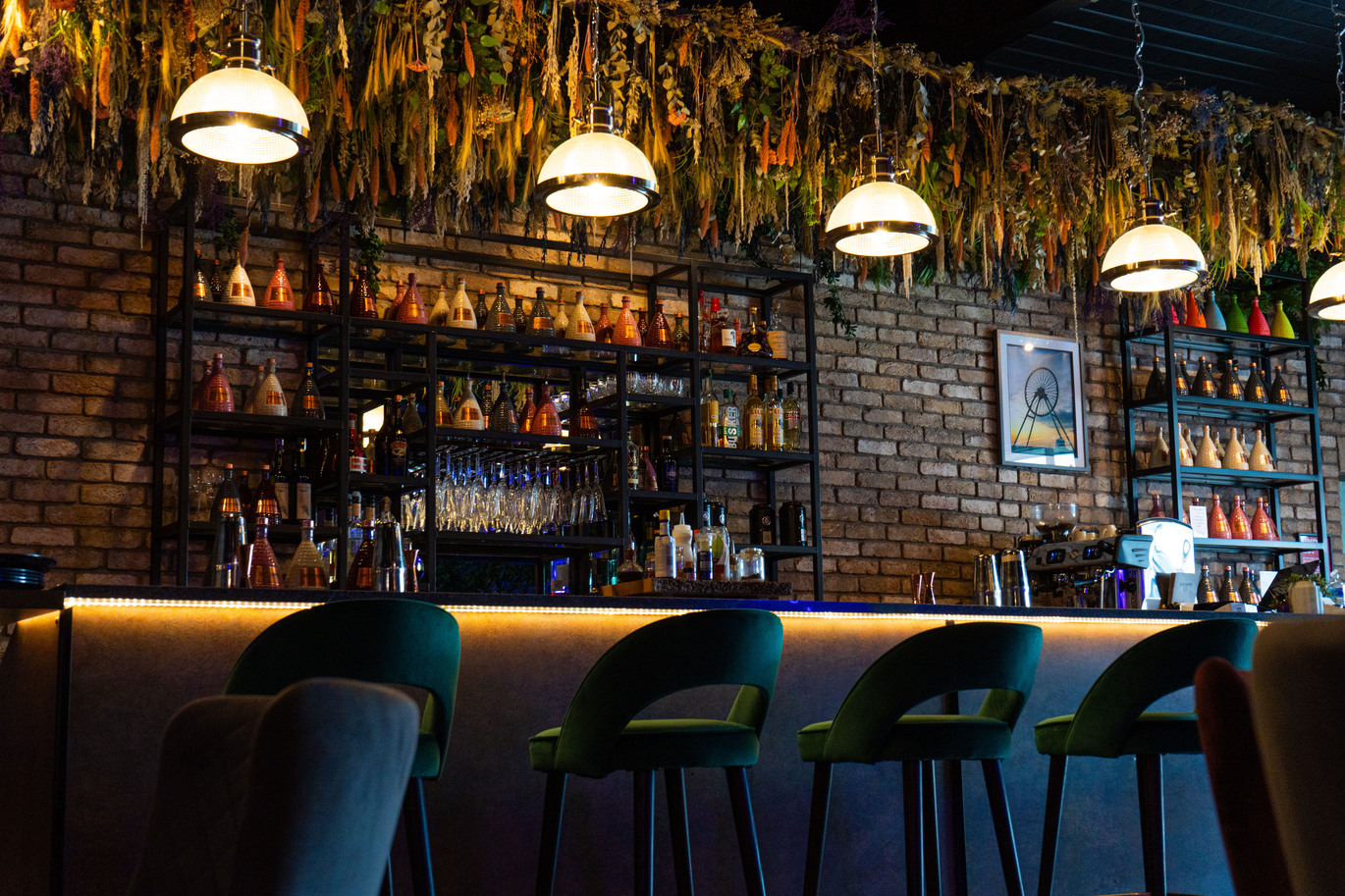''seats in front of a bar area with hanging light above''