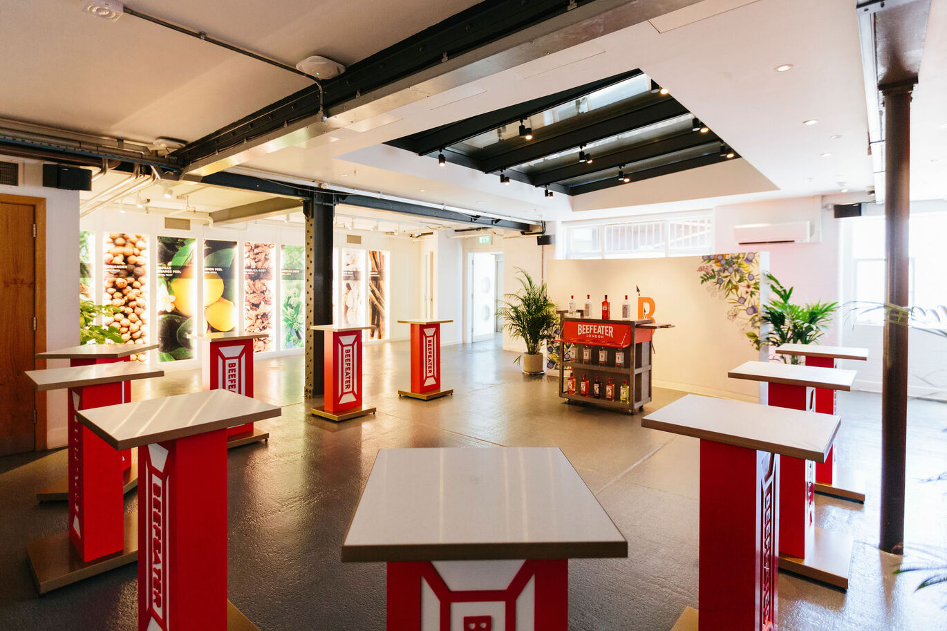 "Photograph of the tasting room, a brightly lit room with a mini bar surrounded by counter height tables"