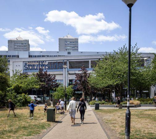 "Pathway leading to Southside Shopping Centre entrance with trees and people walking."