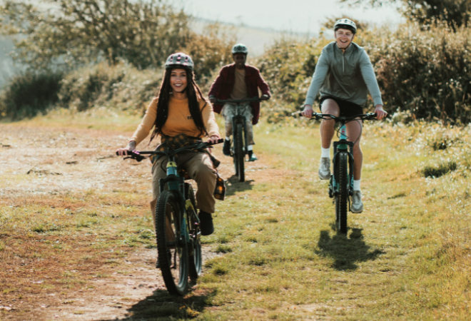 "Three people riding their bikes across a field"