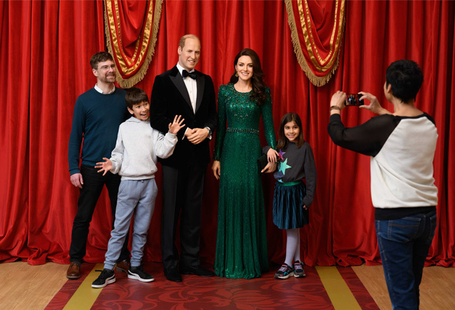 "A group of people posing for a photograph with wax figures of the Prince and Princess of Wales"