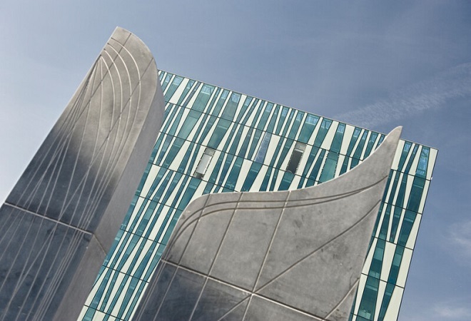 "Exterior image of tall building, taken from below, with blue sky in background"