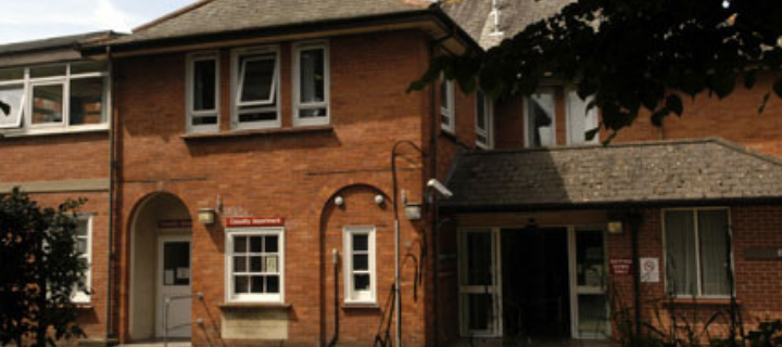 A front-on view of a brick building with red signage around the entrances