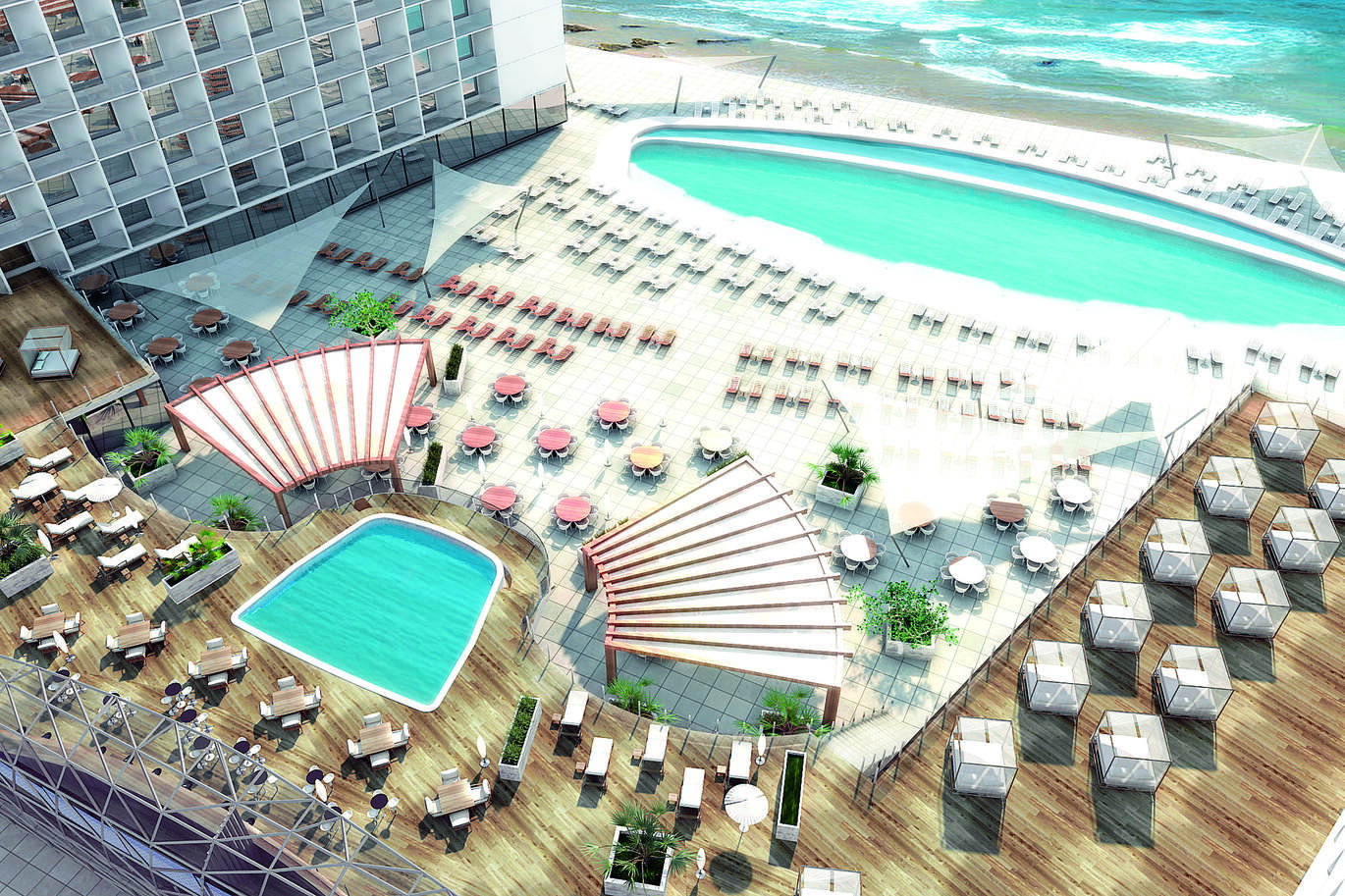 Birdseye view of the pool area with one main large pool on the ground floor surrounded by many sun loungers and an area with tables and chairs behind the pool area. With the beach and sea directly in front. A small second pool is on a higher level with wooden decking around surrounded with tables and chairs with a few sun loungers.