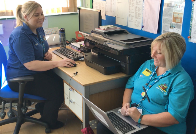 Photo of 2 nurses at a desk talking