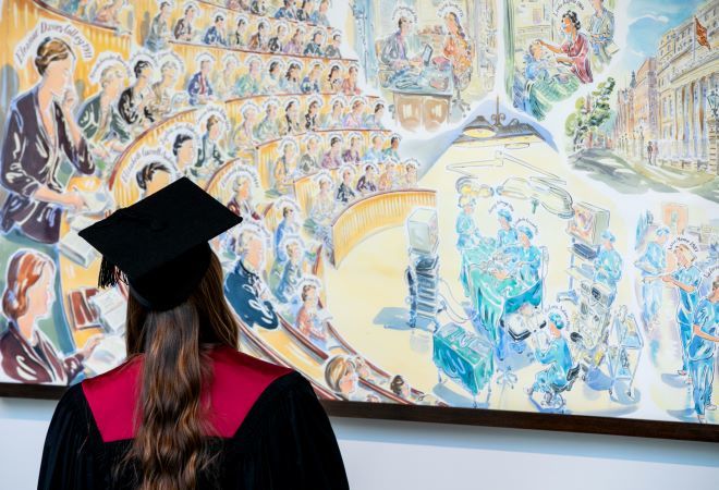Photo of graduate looking at an art canvass.  