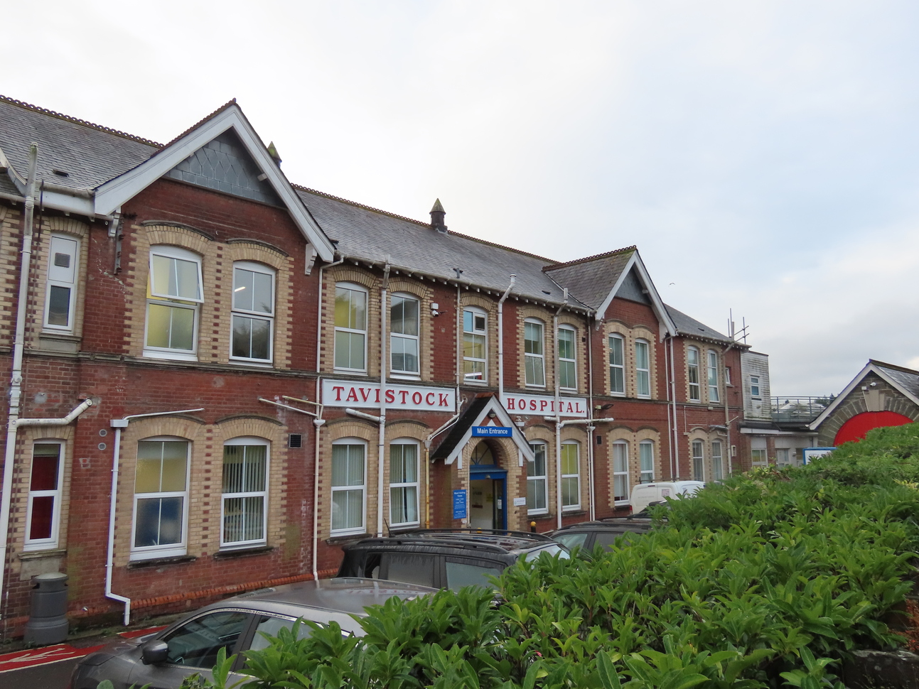 red brick building with blue door and green bush in front 