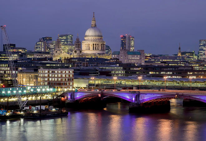 photo of the london skyline, taken from the river thames. st pauls is in the background, with a bridge in view.