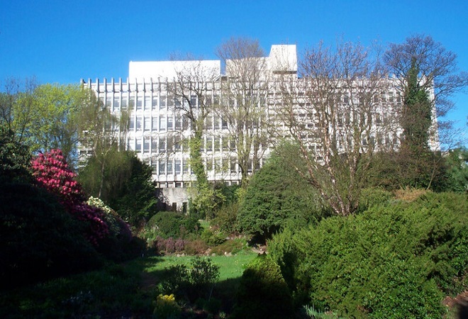 "Image of large University building, taken from a distance with parkland in forefront"