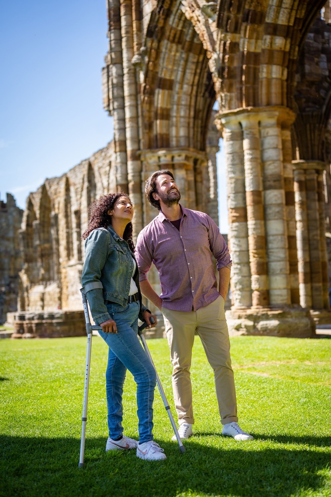"Two people walking next to Whitby Abbey"