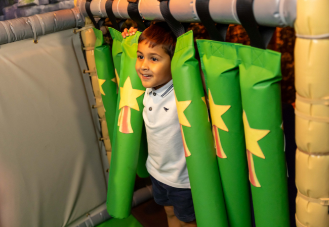 a child walking through a tunnel with green padding 