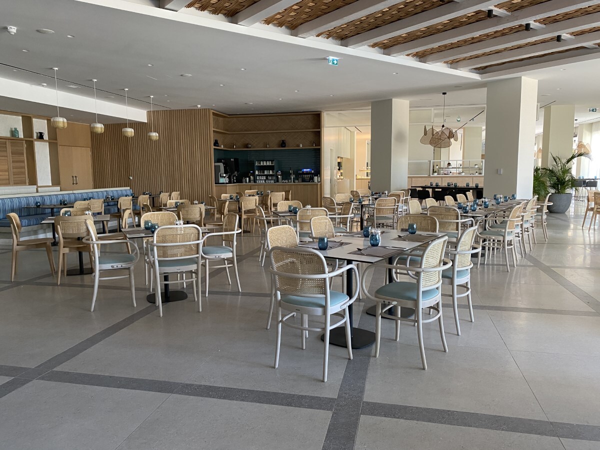 "main restaurant, tables and cheirs spread across large marble floor, there is space between tables."