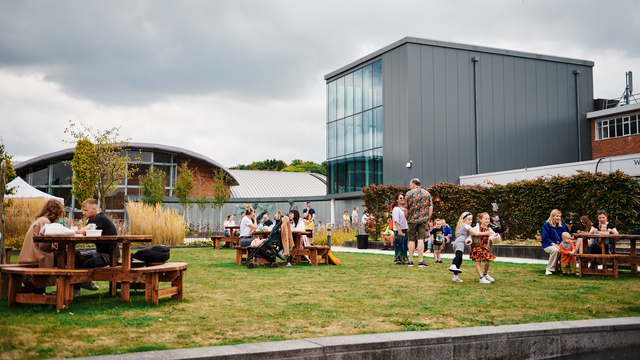 'people sitting on benches in the foreground and black building in the background'