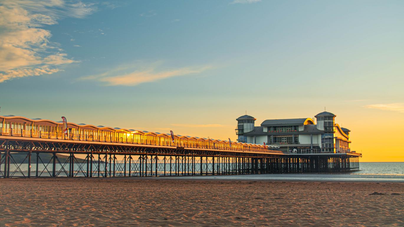 "A view of The Grand Pier at Weston-Super-Mare, Somerset, from the beach at sunset with the tide out."