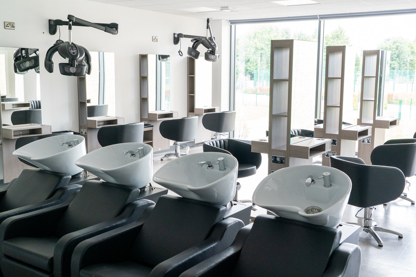 A row of salon chairs and sinks in a well-lit, empty salon room