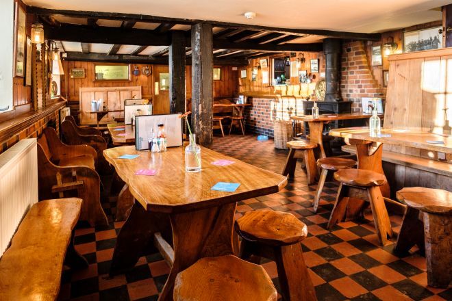 "Internal image of The Harbour Inn showing the carpeted floor, traditional pub tables and benches and the bar in the distance"