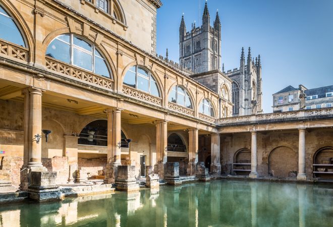 "Roman Baths in Bath, green-blue water surrounded by the roman building itself"