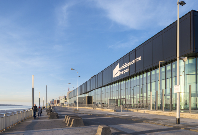 "Glass window building to the right of a path with the words Exhibition Centre Liverpool at the top of building"