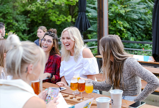 "Photo of a group of friends sitting outside at a BrewDog bar, drinking and laughing"
