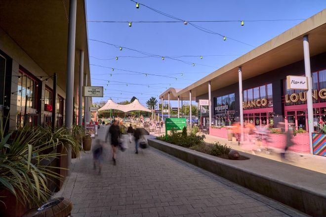 "Outdoor shopping and dining area at White Rose with restaurants, seating and string lights overhead."