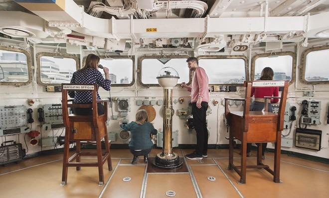 People inside the Navigation Area looking out. 2 chairs are inside, on the left labelled Navigation Officer, on the right labelled Captain