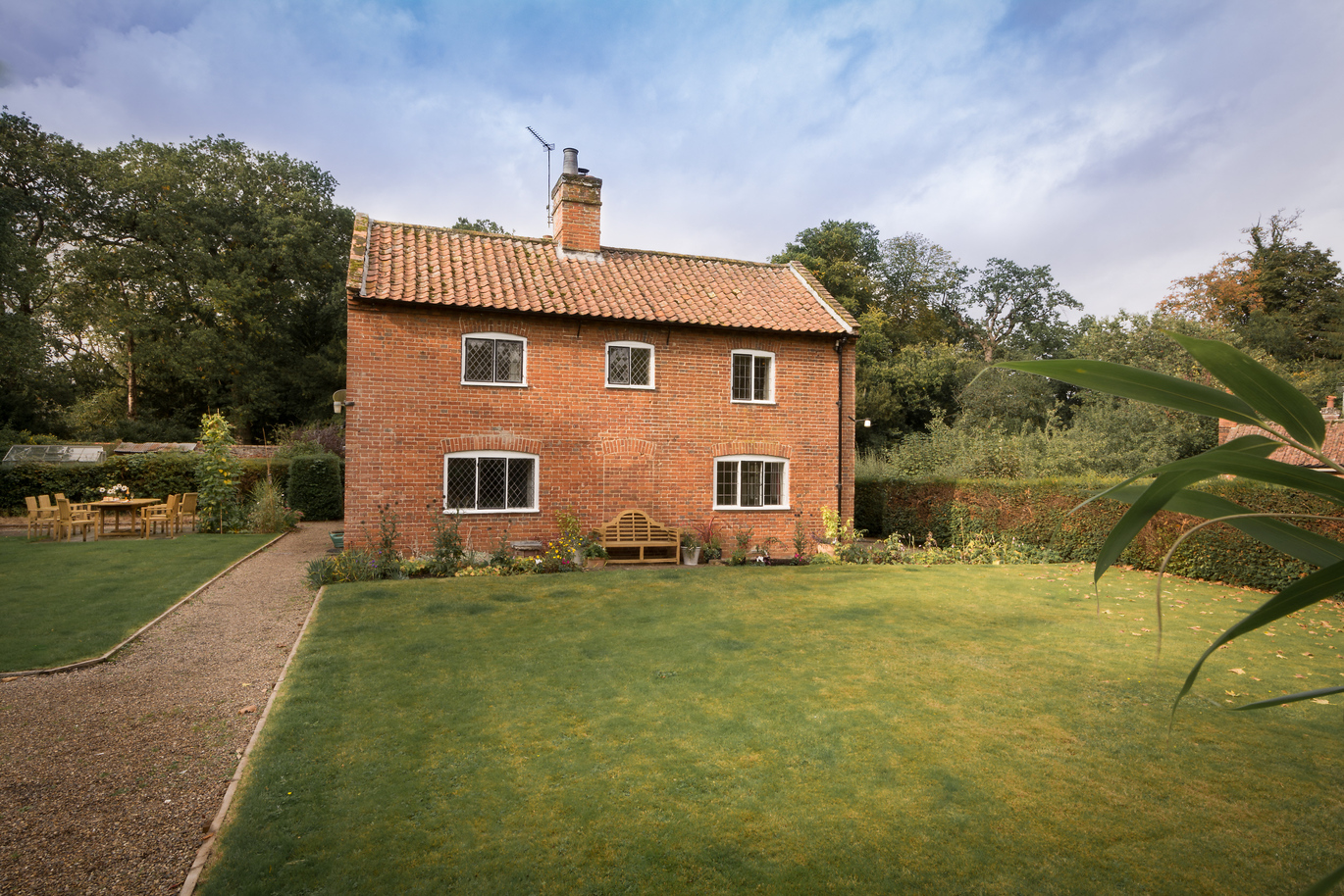 View of the front of the house with the lawn outside and a path down the side.