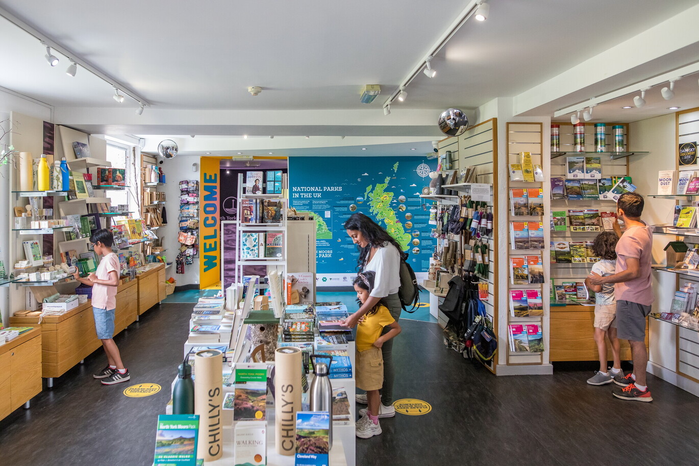 "A number of people, adults and children, are observing toys and books within the Gift Shop"