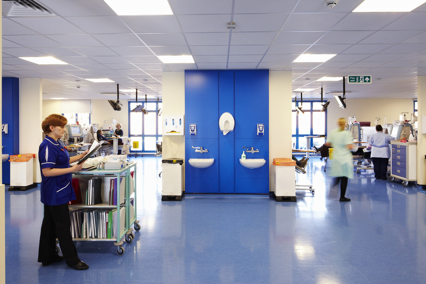 hospital ward with sinks in the back wall and multiple people working 