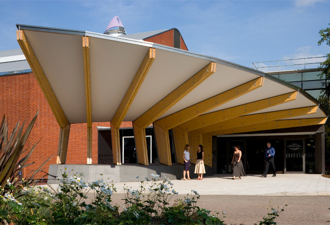 "Building in background with an outdoor terrace leading out on a curve"