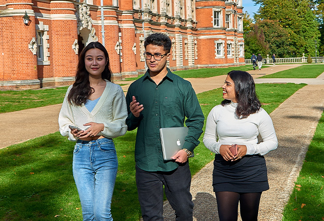 Three students walking on a path on campus